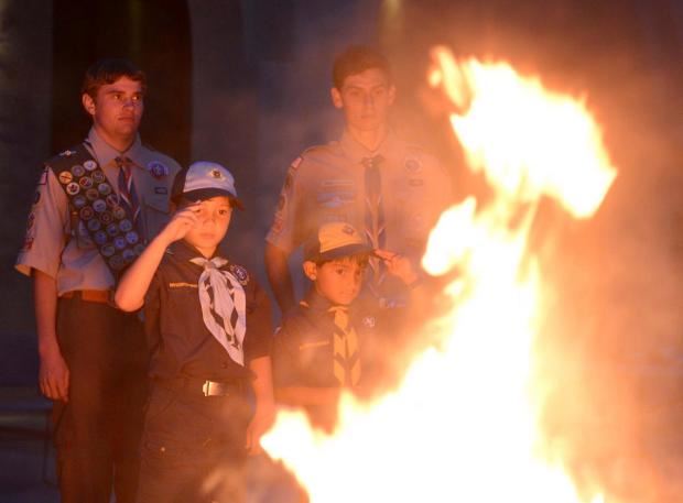 Boy Scout saluting burning flags at ceremony